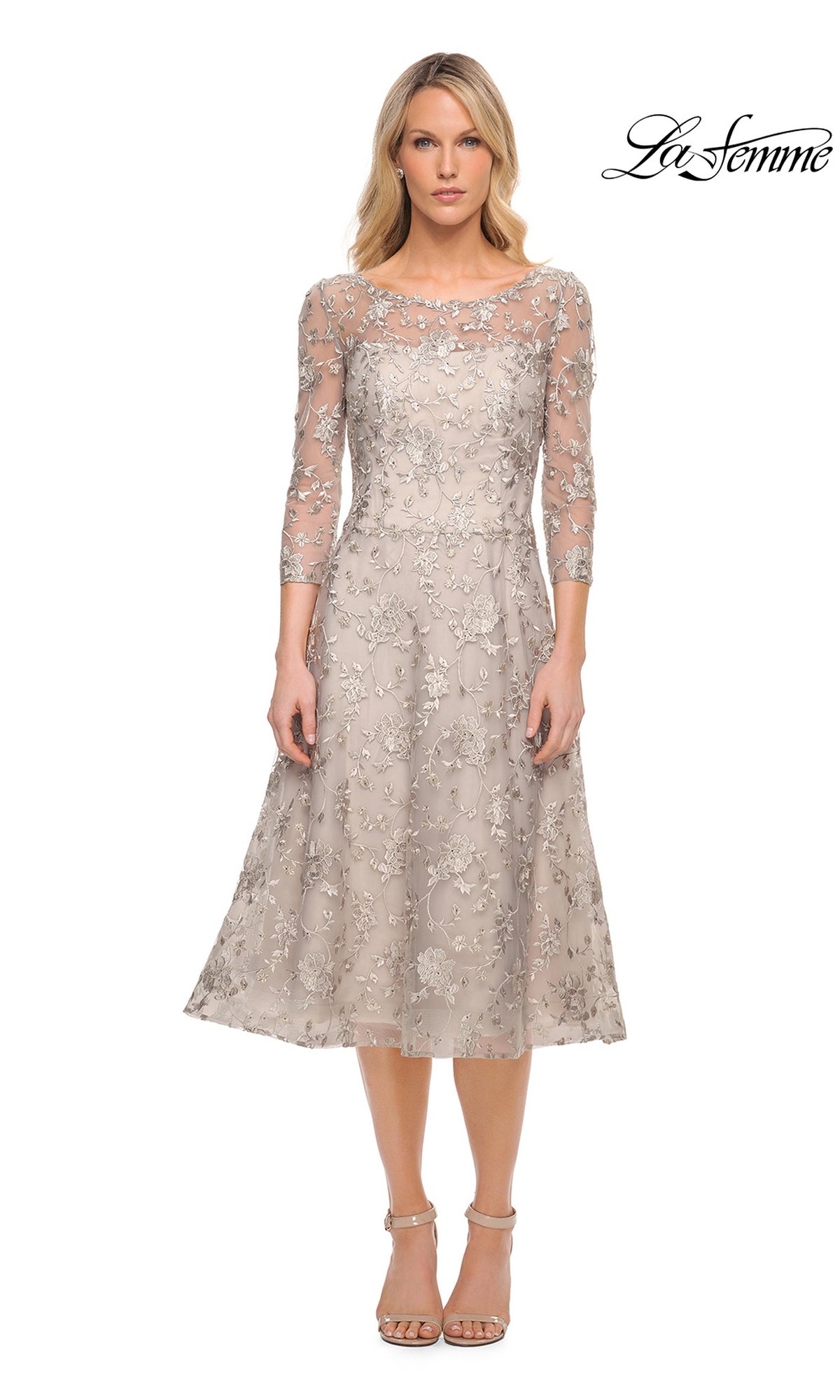 A woman wearing a taupe, midi-length La Femme 30004 wedding guest dress with three-quarter sleeves and a sheer, floral-embroidered lace overlay.
